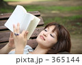 公園のベンチで本を読む女性
