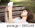 公園のベンチで本を読む女性
