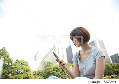 「携帯でメールをする女性」の写真素材