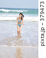 晴れた白い砂浜で水遊びする水着女性