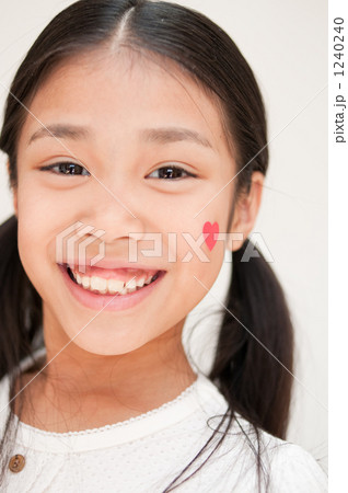 「ハートを頬に貼った女の子」の写真素材 「ハートを頬に貼った女の子」の写真素材