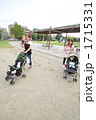 赤ちゃんを抱きベビーカーを押して公園を散歩する2組の若い親子