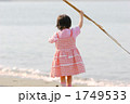砂浜で葦を振り上げる3歳女児