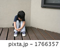 膝を抱えて座る子供