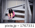 ひざをかかえて座る少女