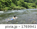 真夏の川に浸かって遊ぶ少年