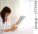 朝食を食べながら新聞を読む女性