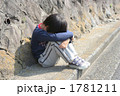 膝を抱えて座る子供