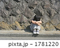 膝を抱えて座る子供