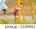 滑り台の支柱に抱きつく2歳の女の子