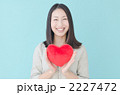 ハートを持つ20代の女性（ブルーバック）