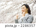 桜とガッツポーズをする女性