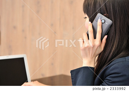 スマートフォンで話すビジネスウーマン(カフェ・後姿)