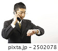 時計をみながら電話する男性