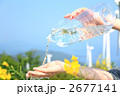 風力発電機の並ぶ自然とペットボトルの水と女性の手