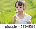 たんぽぽの綿毛を吹く3才の女の子