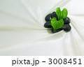 白い布の上の黒石とハート型の葉っぱ