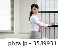 棚からファイルを取り出すビジネスウーマン