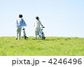 草原で自転車を押すカップルの後姿