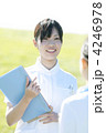 草原でファイルを持ち微笑む看護師