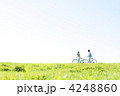 草原で自転車を押すカップル