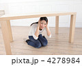 机の下に隠れる女性