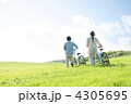 草原で自転車を押すカップルの後姿