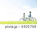 草原で自転車を押すカップル