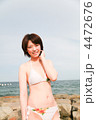頬に手を当てる・笑う／カメラ目線／真夏の海岸浜辺／若い水着の女性