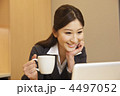 コーヒーを手にノートPCを見る女性ビジネスマン
