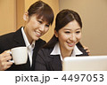 コーヒーを手にノートPCを見る２人の女性ビジネスマン