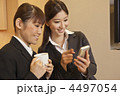 コーヒーを手にスマートフォンを見る２人の女性ビジネスマン