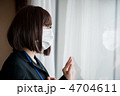 窓の向こうを見つめるマスクをしたビジネスウーマン