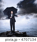 雨の海岸で傘をさしている男性