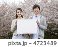 桜をバックにメッセージボードを持ったカップル