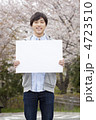 桜をバックにメッセージボードを持った男性