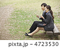 公園のベンチでサンドイッチを食べている男女ビジネスマン