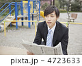 公園のブランコで新聞を読むビジネスマン