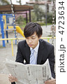 公園のブランコで新聞を読むビジネスマン