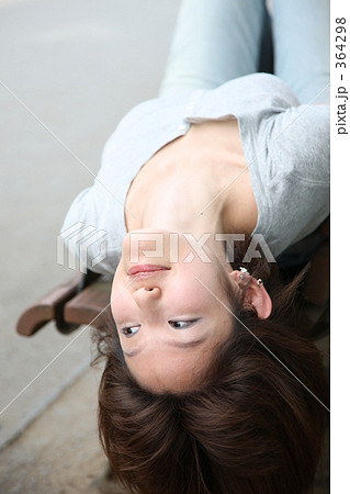 ベンチで仰向けに寝る女性の写真素材