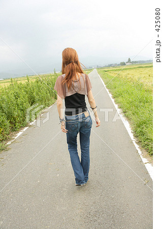 女性 後ろ姿 道の写真素材