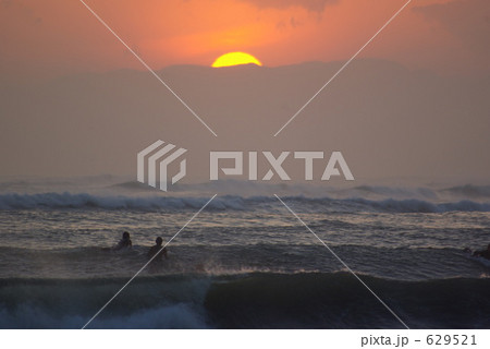 落日を眺めるサーファー 629521
