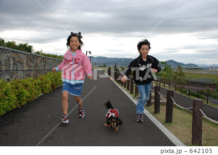 少女２人走って犬の散歩の写真素材