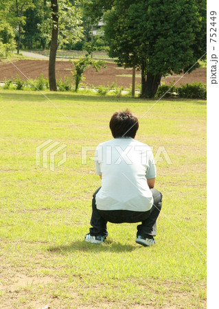 芝生の上 しゃがんでる 男性の写真素材