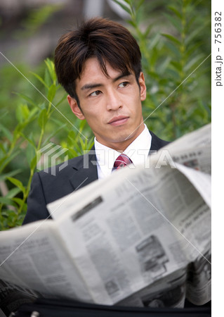 公園のベンチで新聞を読むビジネスマン 756382