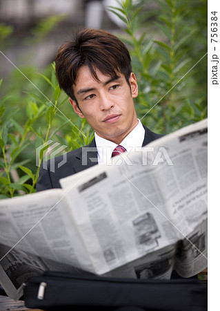 公園のベンチで新聞を読むビジネスマン 756384