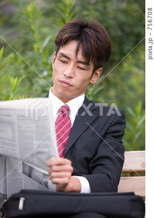 公園のベンチで新聞を読むビジネスマン 756708