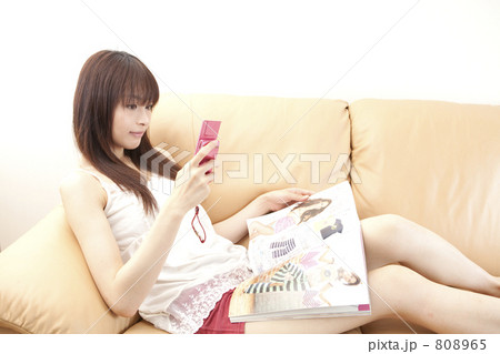 雑誌を見ながら携帯する女性 808965
