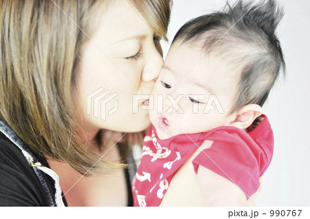 新生児と若い母親 赤ちゃんのほっぺにキスの写真素材