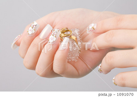 ガラス小物を持つ白バラ柄とパールとストーンのネイルチップをつけた手 1091070
